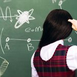 A woman looks at a blackboard.