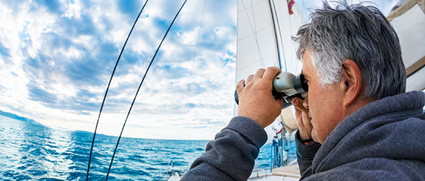 Person using binoculars on a yacht.