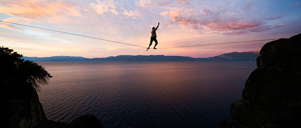A tightrope walker with a body of water in the background.
