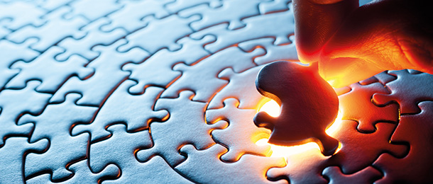 A hand places the final jigsaw piece in the centre of a jigsaw.