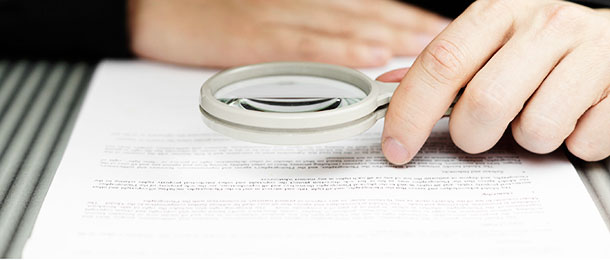Someone looks through a magnifying glass at a document.