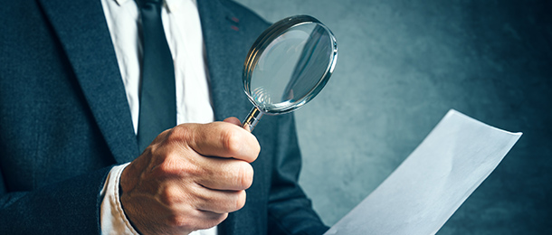 Man looks at a document through a magnifying glass