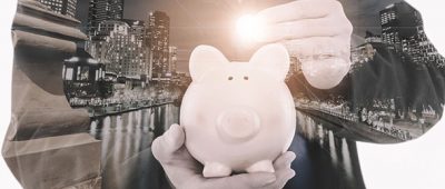 A human hand holding a pale pink piggy bank