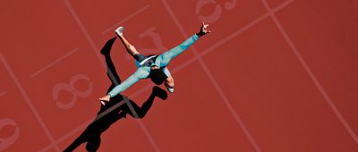 A runner sprints over the finish line ahead of his competitors.