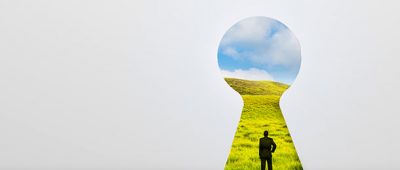 Looking through a keyhole towards a person standing on grassy green hills