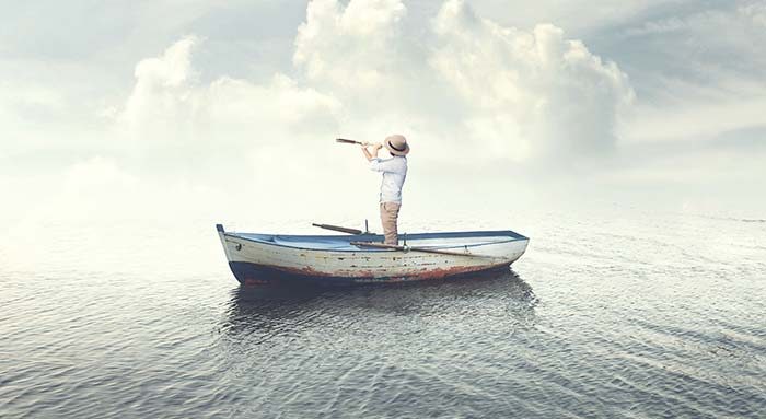 Man standing in small boat using telescope